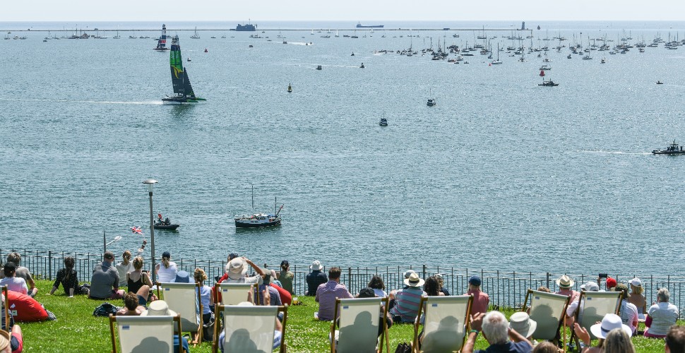 People sat in deckchairs on Plymouth Hoe watching the Australian SailGP team go past